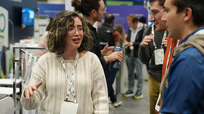 A Mila student researcher presenting her work to attendees at the NeurIPS conference.